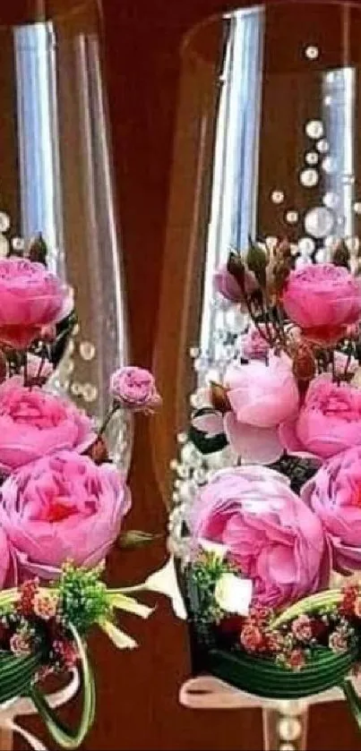 Two champagne glasses with pink roses and pearl decorations.