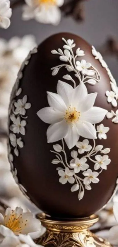 Chocolate egg with white floral designs on a blurred background.