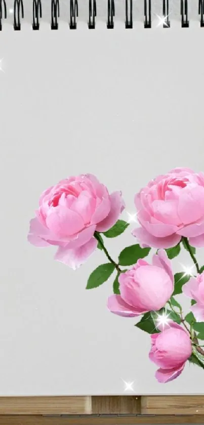 A notebook with pink roses between two potted plants.