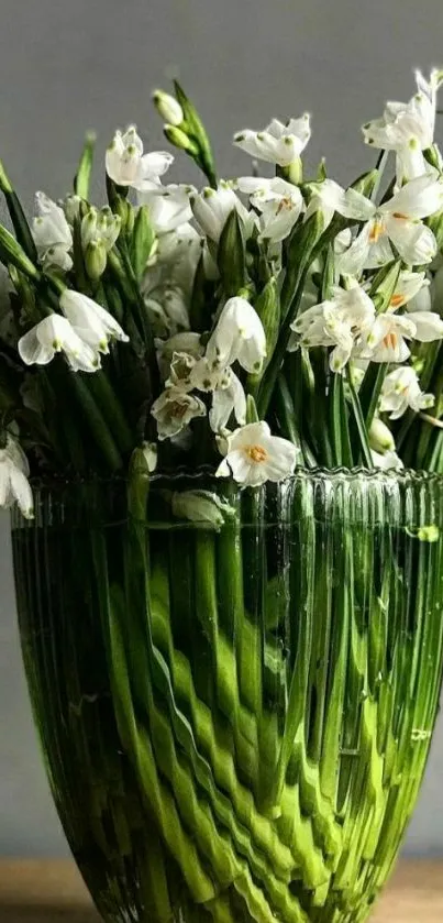 Green vase with white flowers in a soft light.