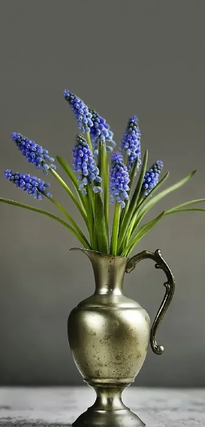 Vintage bronze vase with purple flowers on gray background.