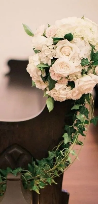 Elegant floral bouquet with roses and ivy on a church bench for wedding decor.