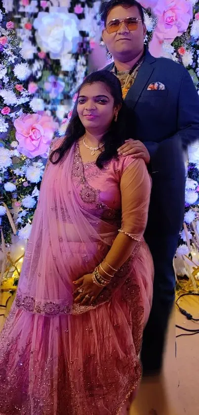 Elegant couple in pink and floral backdrop for a wedding.