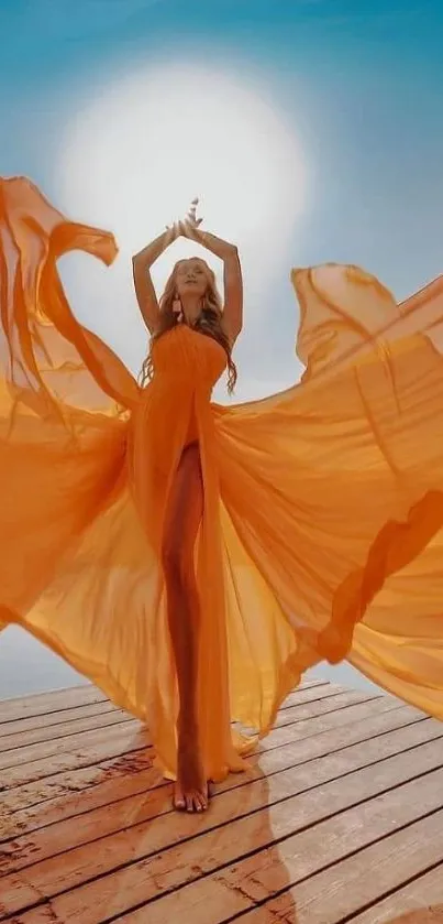 Woman in flowing orange dress under the sun on a wooden deck.