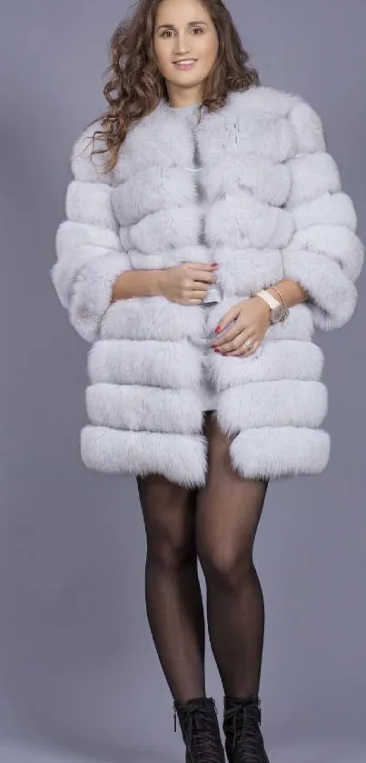 Woman in elegant fur coat against gray background.