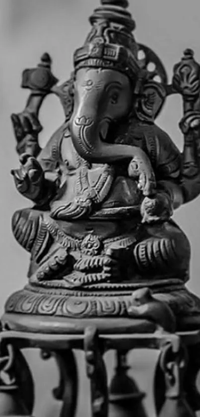 Black and white Ganesha statue with bells in a tranquil setting.