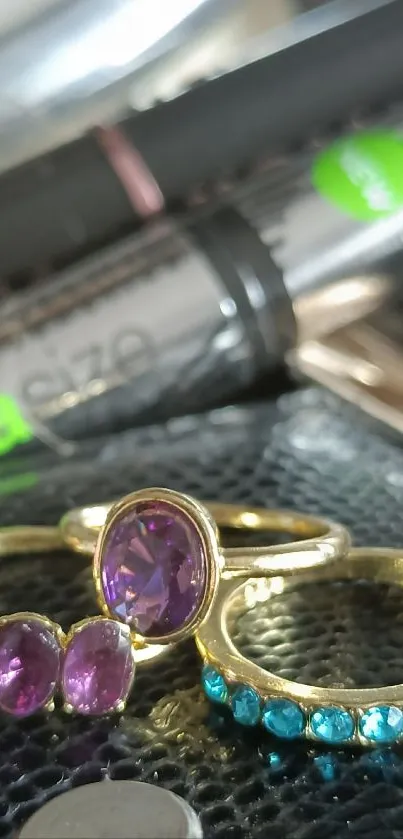 Close-up of gold rings with purple and blue gemstones on a stylish background.