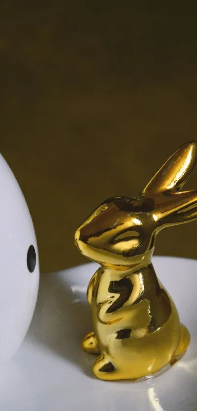 Golden bunny statue beside a polka-dotted egg on a minimalist plate.