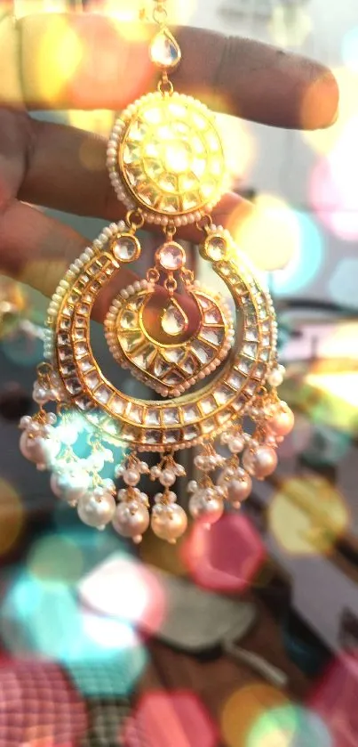 Close-up of a gold earring with gemstones in hand.