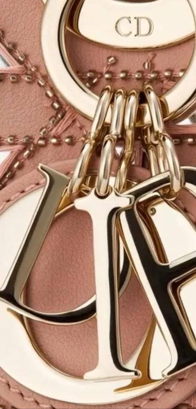 Close-up of a gold letter keychain on a pink textured background.
