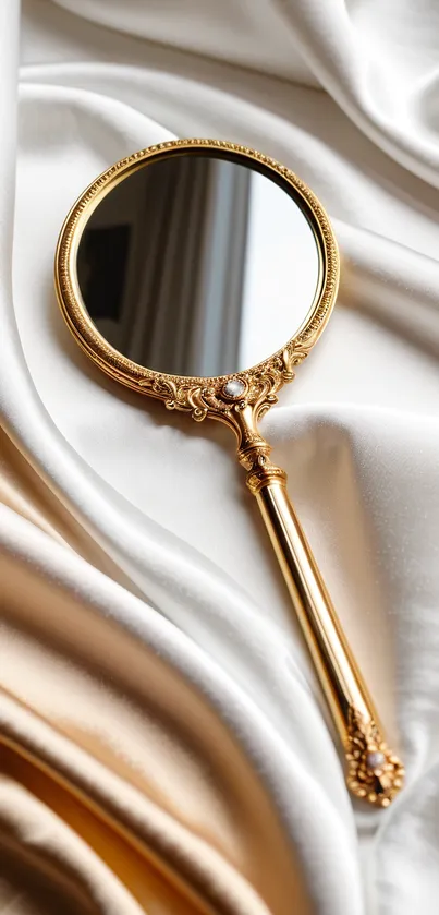 Elegant gold handheld mirror on creamy satin.