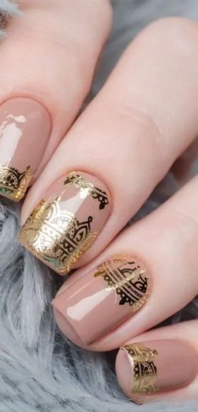 Close-up of chic nude nails with intricate gold art, draped on a soft fur surface.