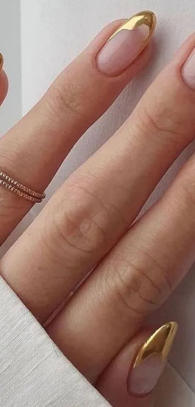 Close-up of elegant gold-tipped manicure with rings.