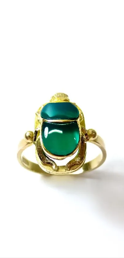 Gold scarab ring with green stones on a white background.