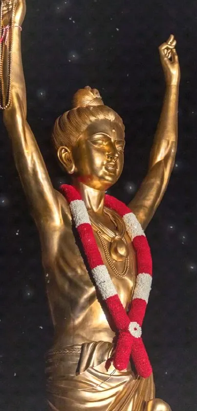 Golden statue with red and white garland on black background.