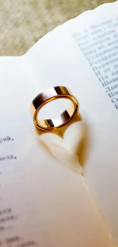 Golden ring casting heart shadow on open book page.