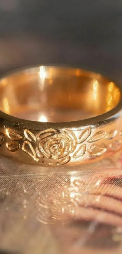 Golden ring with floral engravings on reflective surface wallpaper.