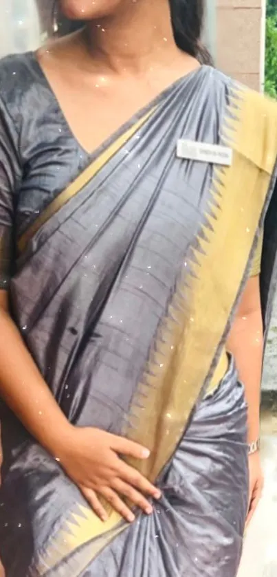 Elegant gray saree with gold accents and subtle background.