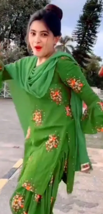 Woman in green dress with floral design outdoors.