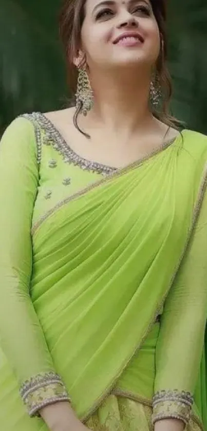 Woman in a vibrant green saree with intricate design standing outdoors.