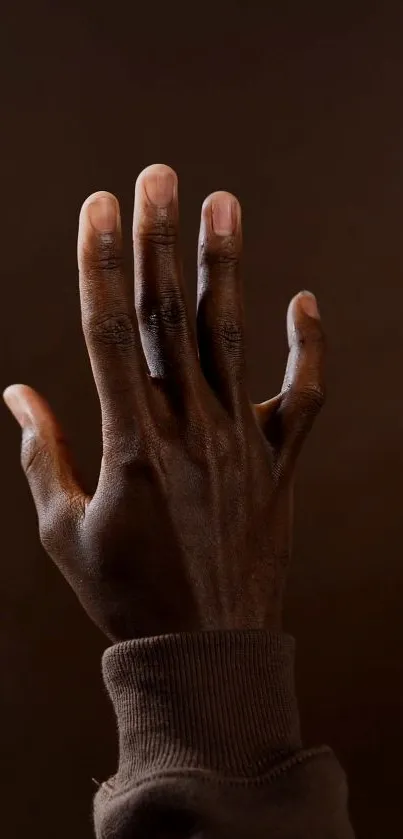 Elegant hand gesture against a dark brown background.