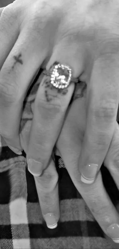 Black-and-white hands with tattoos and a ring.