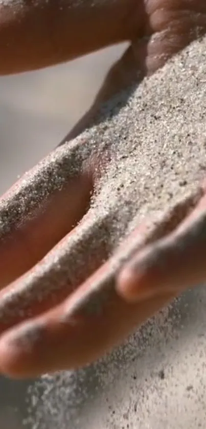 Close-up of a hand letting sand flow gently through fingers.