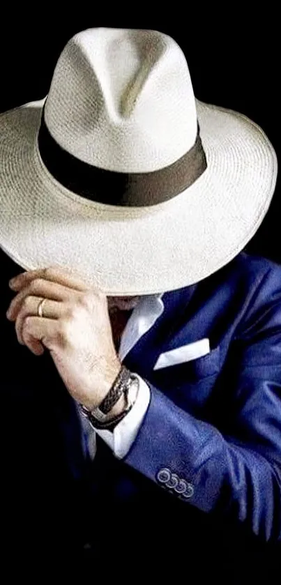 Man in blue suit and white hat on black background.