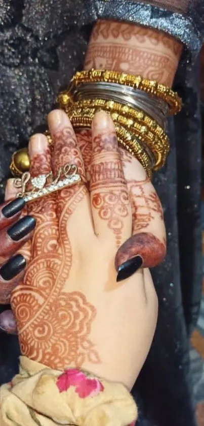 Intricate henna design with gold bangles on a hand.