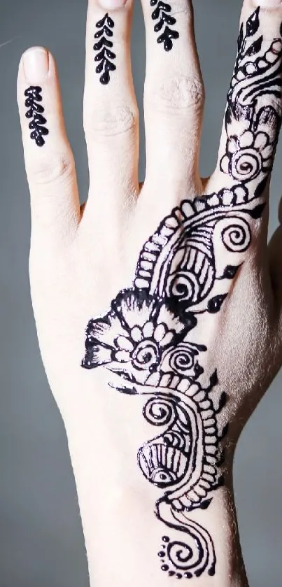 Intricate black henna design on hand against light background.