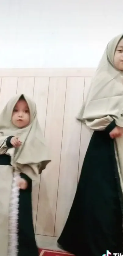 Two young girls in matching abayas and hijabs.