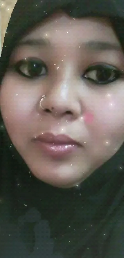 Portrait of a woman in a black hijab with a subtle sparkle effect.