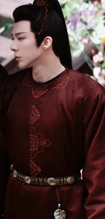 Person in rich burgundy historical attire with a floral backdrop.