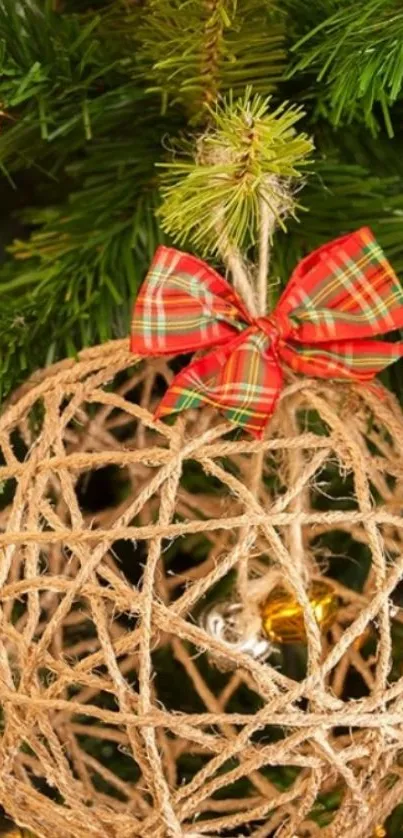 Christmas twine ball ornament with plaid bow on pine tree.