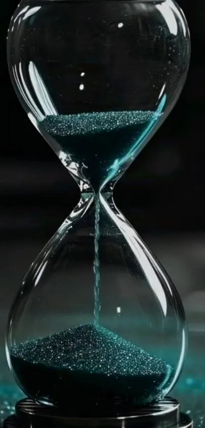 Hourglass on black background with teal sand.