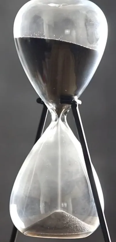 Elegant hourglass with black sand on a gray background.