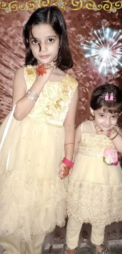 Two young girls in festive beige dresses, smiling warmly.