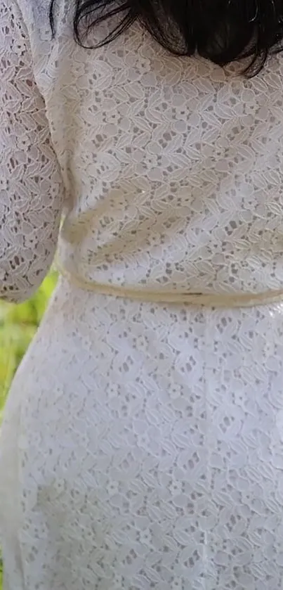 Back view of woman in elegant white lace dress in a garden.