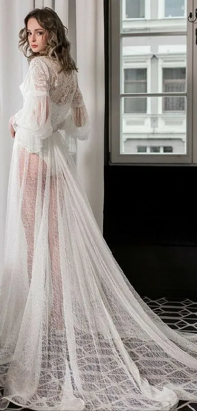 Woman in elegant white lace gown by the window.