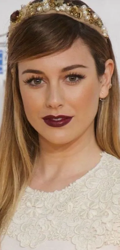 Woman in elegant lace outfit with jeweled headband on neutral backdrop.