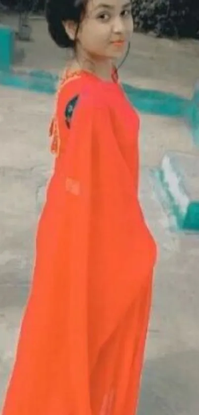 Woman in a vibrant red saree standing elegantly.