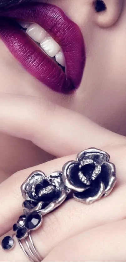 Close-up of purple lips with floral ring jewelry.