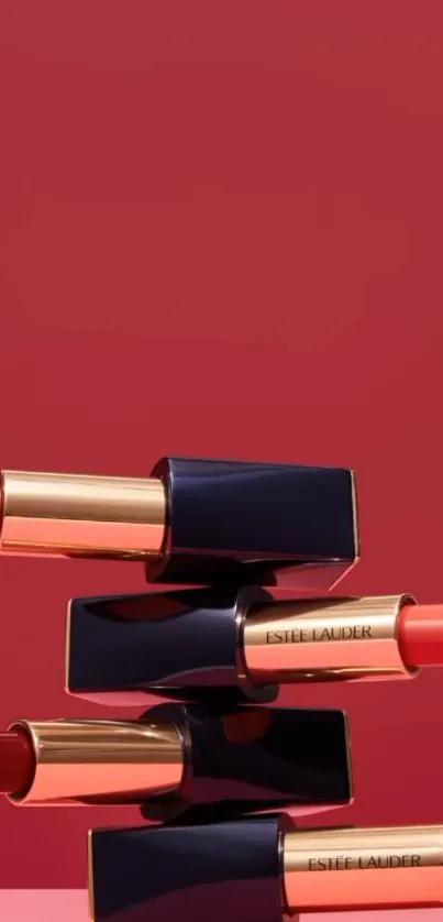 Stacked luxury lipsticks against red background.