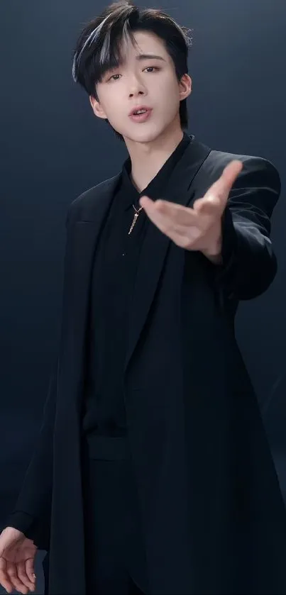 Stylish young man in a sleek black suit on a dark background.