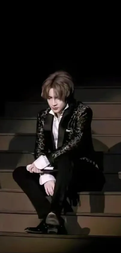 Elegant man in formal attire sitting on stairs with dark background.