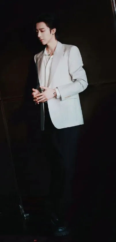 Stylish man in a white suit against a dark backdrop.