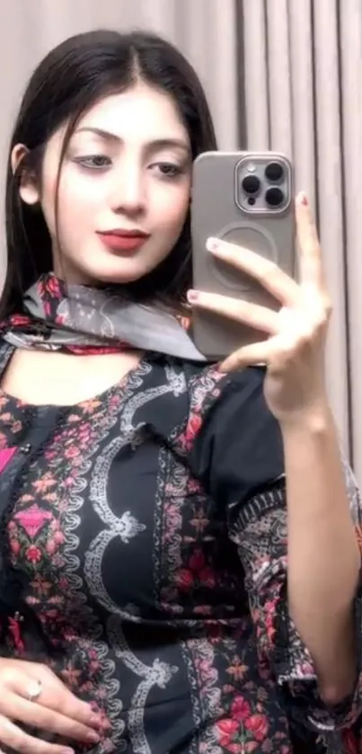 Stylish woman taking a mirror selfie in intricate attire.