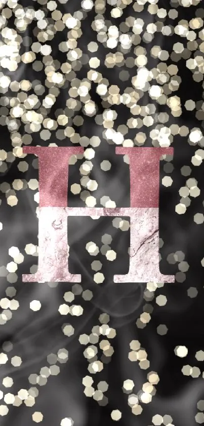 Elegant 'H' monogram with bokeh light effects on black background.