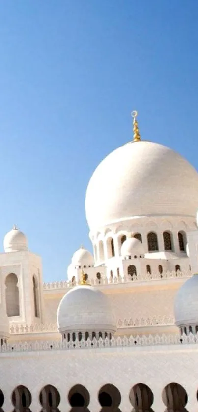 Elegant mosque with white domes under clear blue sky.