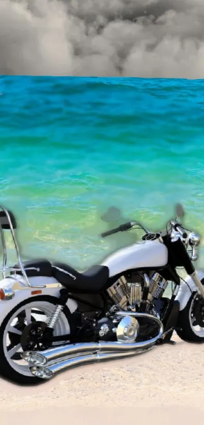 Motorcycle parked on a sandy beach with turquoise sea and cloudy sky.